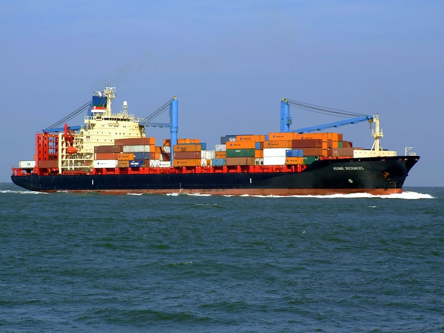 container vans on black and white cargo ship on water under blue sky