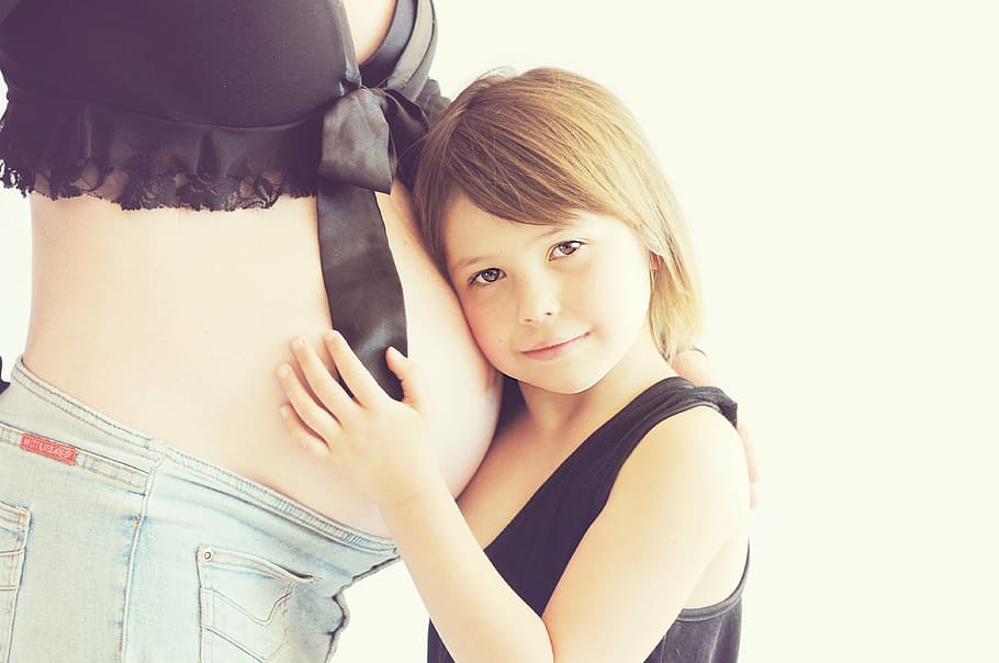 boy in black tank top leaning on woman's belly, pregnant, pregnancy