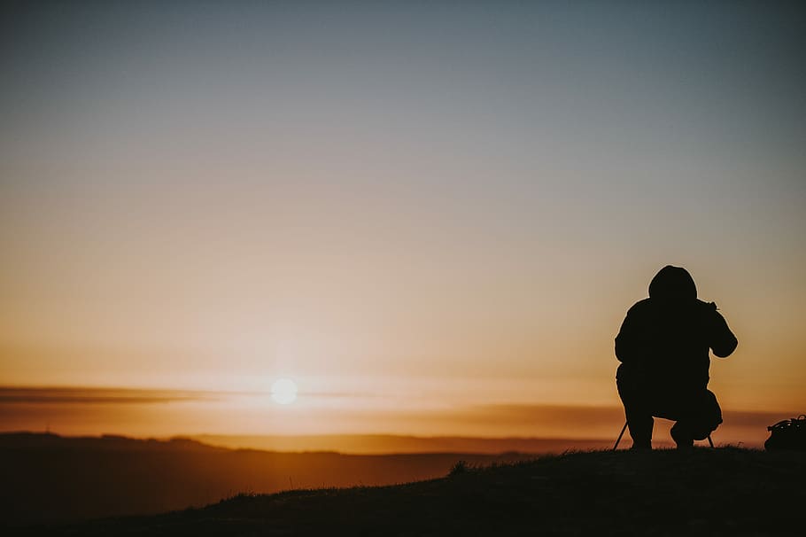 person using camera during daytime, silhouette of person sitting on hill HD wallpaper