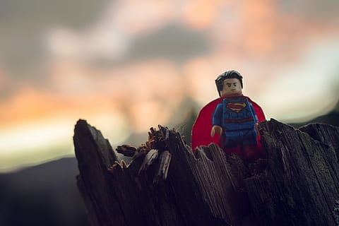 Lego Superman mini figure on tree trunk, Lego Superman minifigure on brown wooden surface HD wallpaper