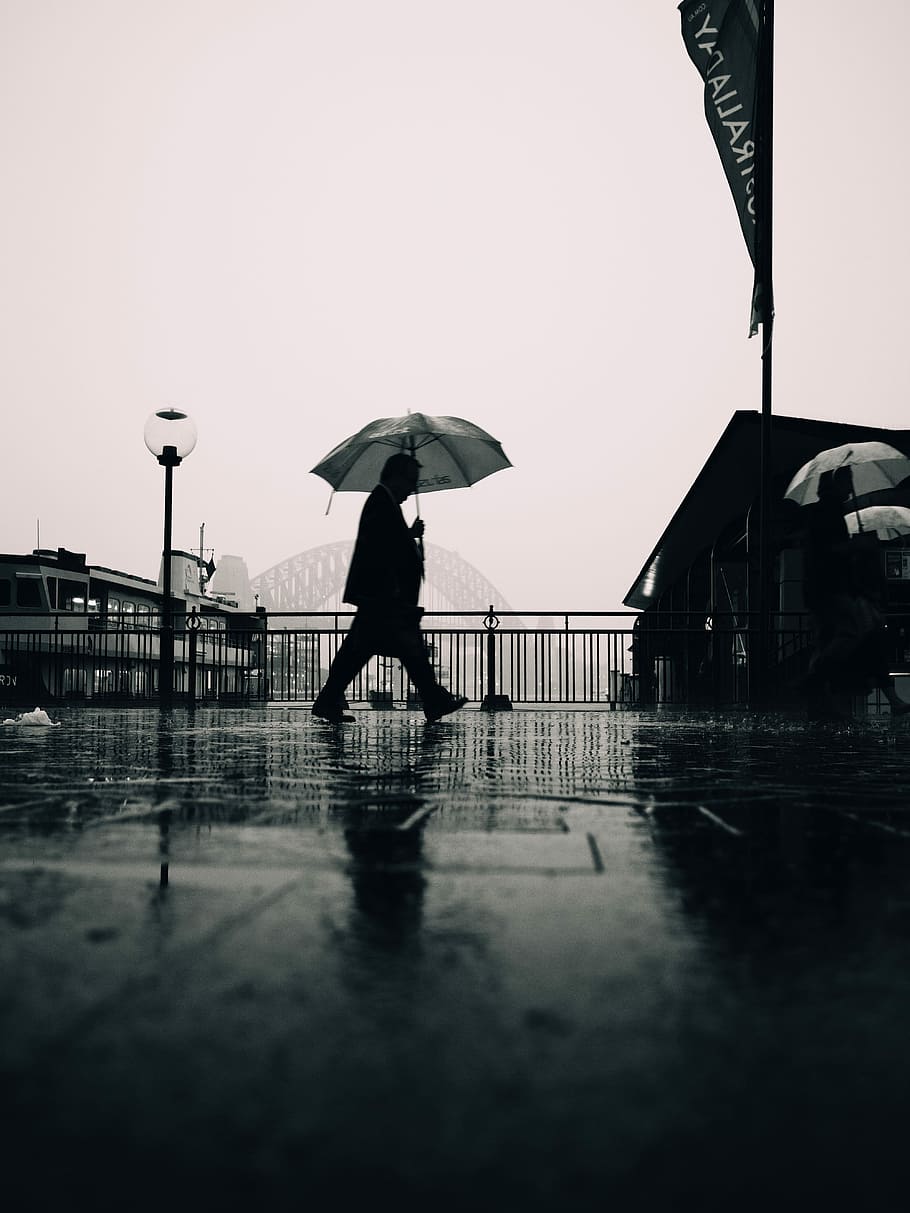person walking under umbrella nearby Sydney Harbour Bridge, Australia