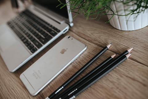 Silver Acer laptop on a wooden desk with a green plant, pencils and an Apple iPhone HD wallpaper