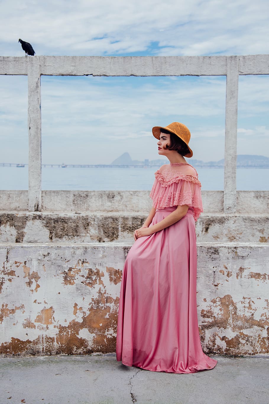 woman in pink dress standing beside wall during daytime, floor