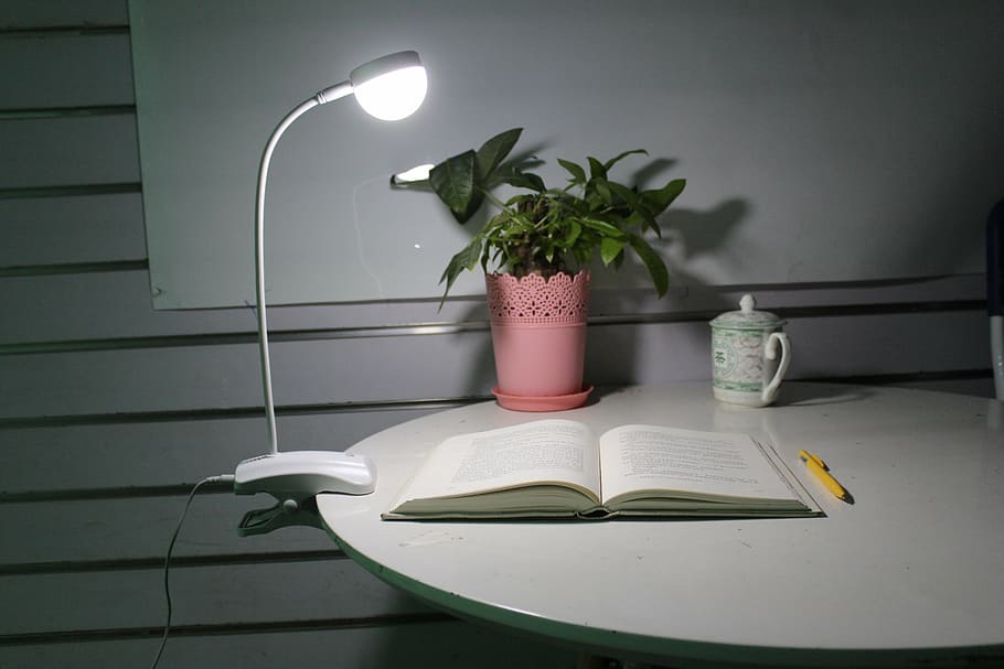 yellow pen beside white open book on desk with clip-on table light turned on, HD wallpaper