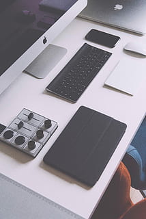 silver iMac, Apple cordless keyboard, traction pad, silver Macbook, and tablet case on white table HD wallpaper