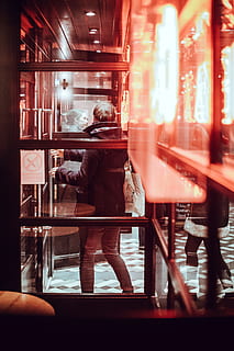 man standing near glass wall, person can be seen through window with brown wooden frames HD wallpaper