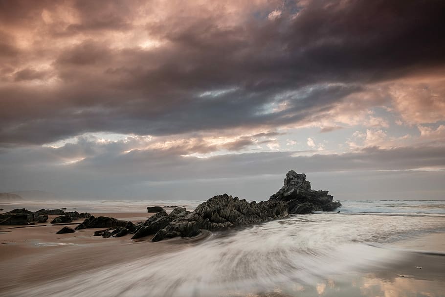 body of water near rock formation with nimbus cloud, landscape photo of rock formation HD wallpaper