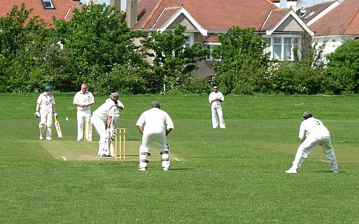 group of men playing cricket game on green grass field during daytime HD wallpaper