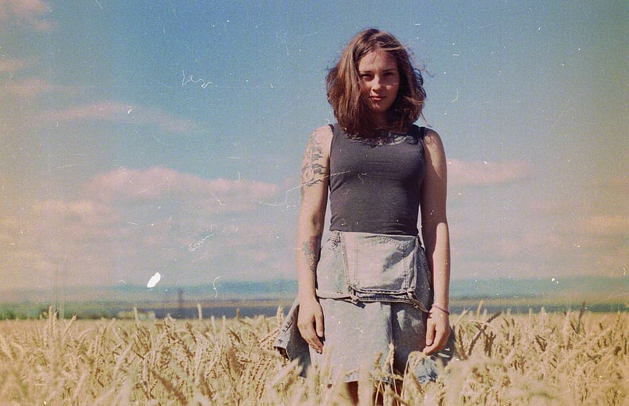 woman standing on brown field, woman in black top on brown field under blue sky