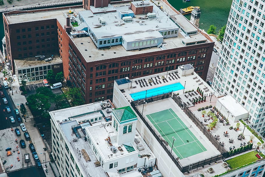 aerial view photo of tennis court and swimming pool on top of building along the road, The Life