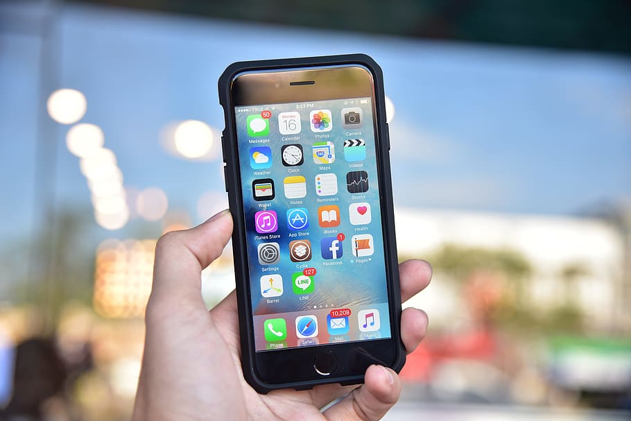 selective focus photography of person holding turned-on iPhone HD wallpaper