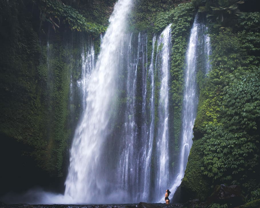 time lapse photography of waterfalls, woman standing beside waterfalls at daytime HD wallpaper