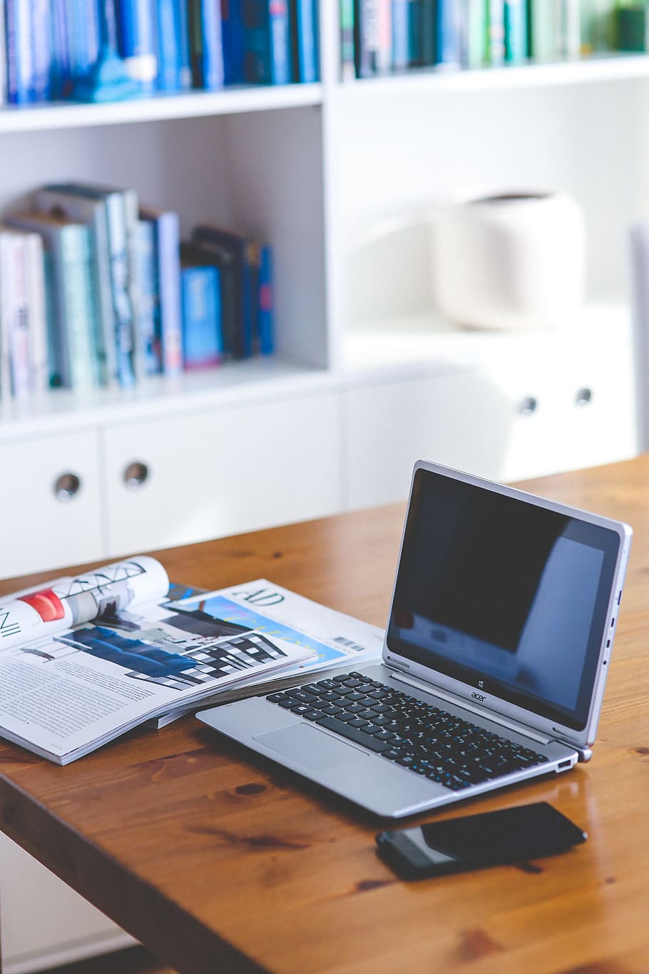 grey Acer laptop on brown wooden table beside magazine and smartphone HD wallpaper