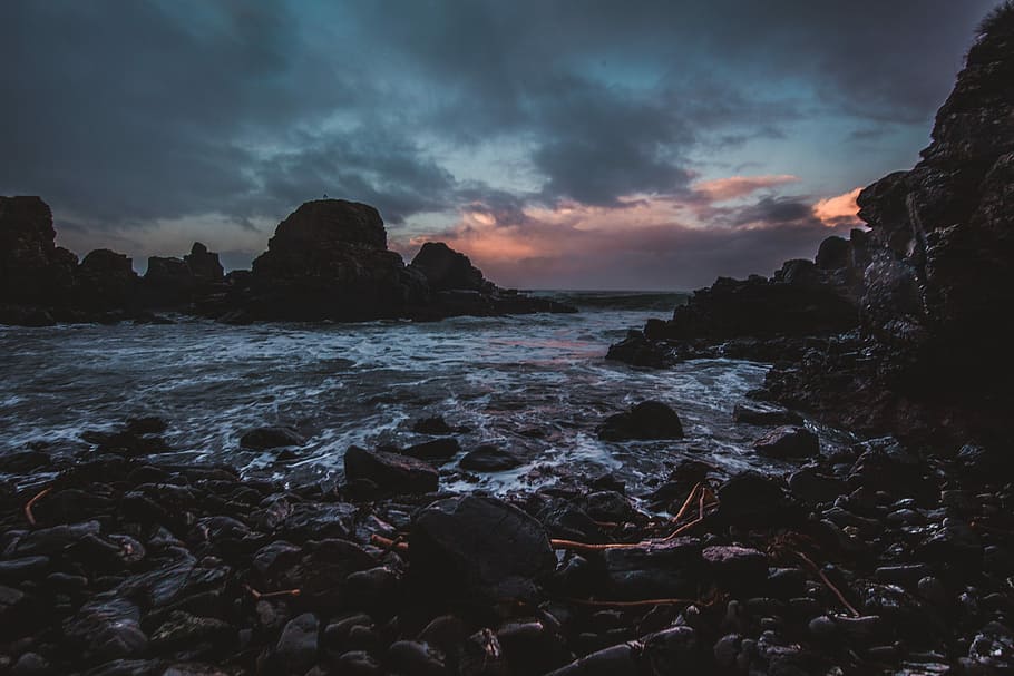 rocky body of water under gray sky, water splashing on brown rocks HD wallpaper
