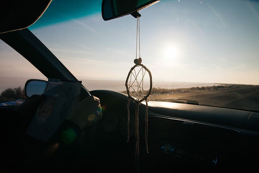 HD wallpaper: dreamcatcher hanged from rear view mirror inside car driving  on road along shore during golden hour | Wallpaper Flare