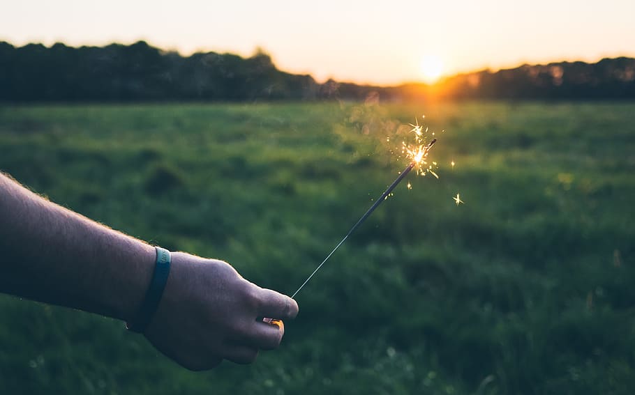 person holding fire stick, person holding sparkler during sunset HD wallpaper
