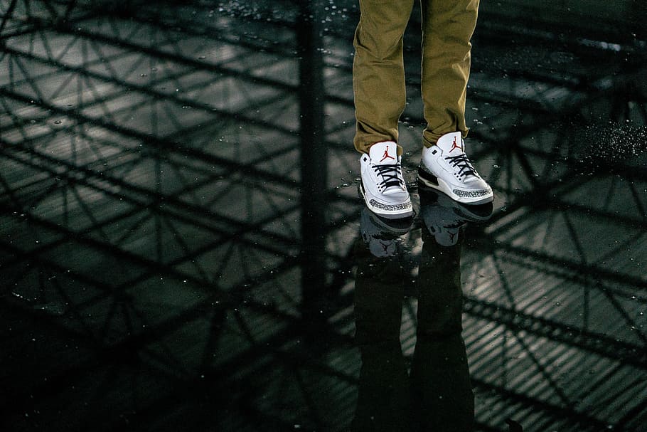 person wearing Air Jordan basketball shoes, pair, white, black