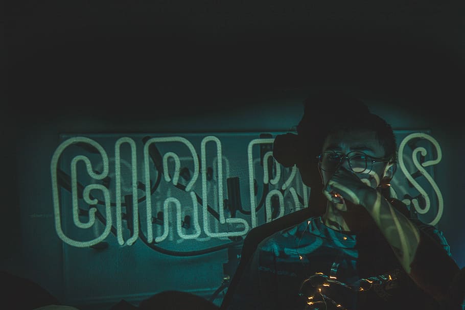 person wearing eyeglasses on green neon signage in dark room, person standing near wall with neon signage HD wallpaper