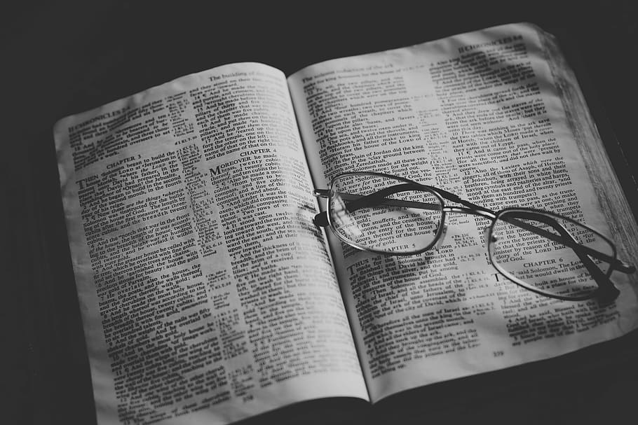 grayscale photo of eyeglasses on top of book, eyeglasses on opened book
