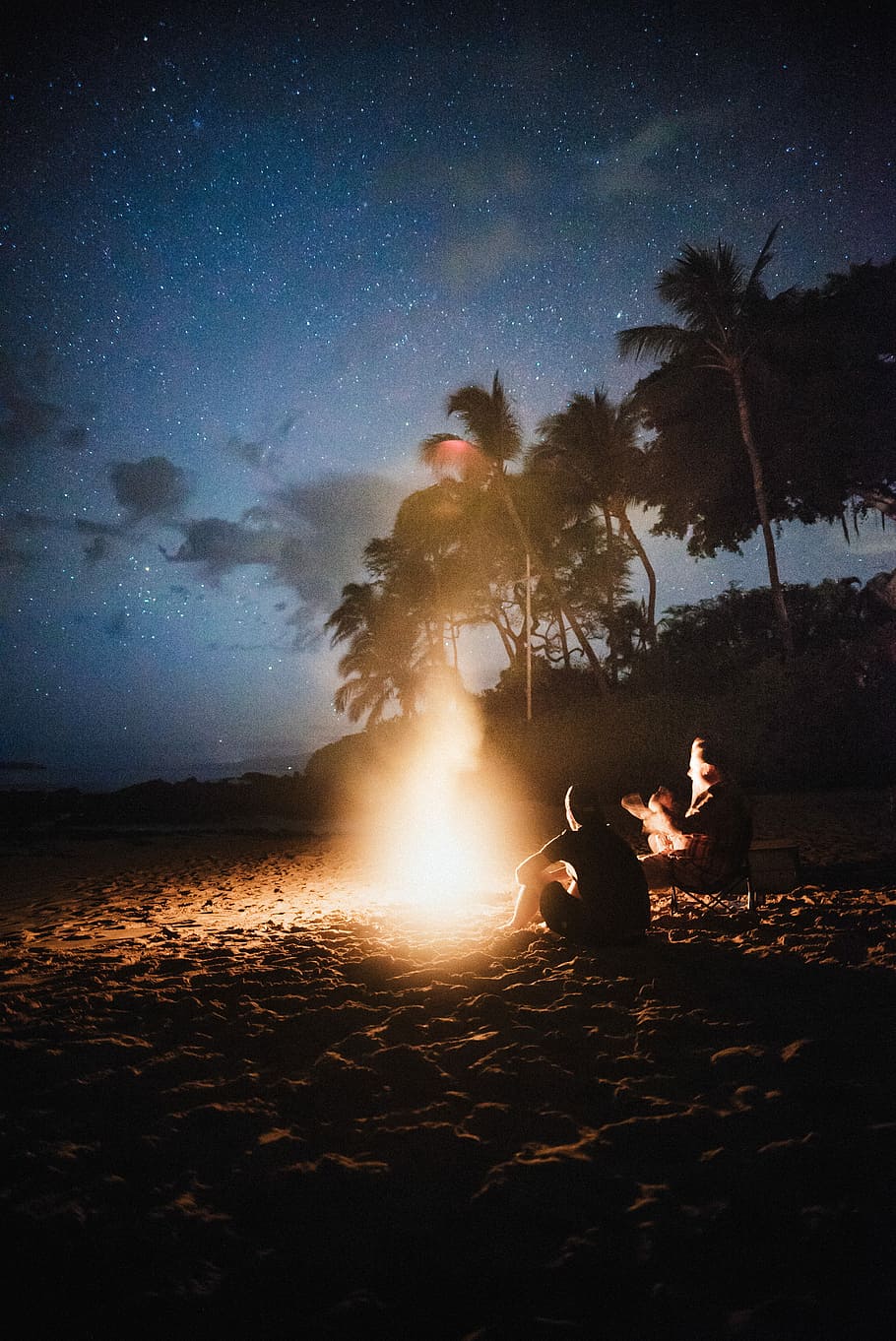 time lapse photography of bonfire, silhouette of man and woman sitting near bonfire on seashore HD wallpaper