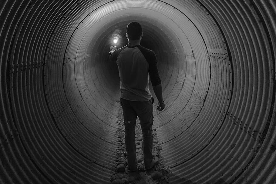 person standing inside the tunnel, grayscale, man, guy, flare