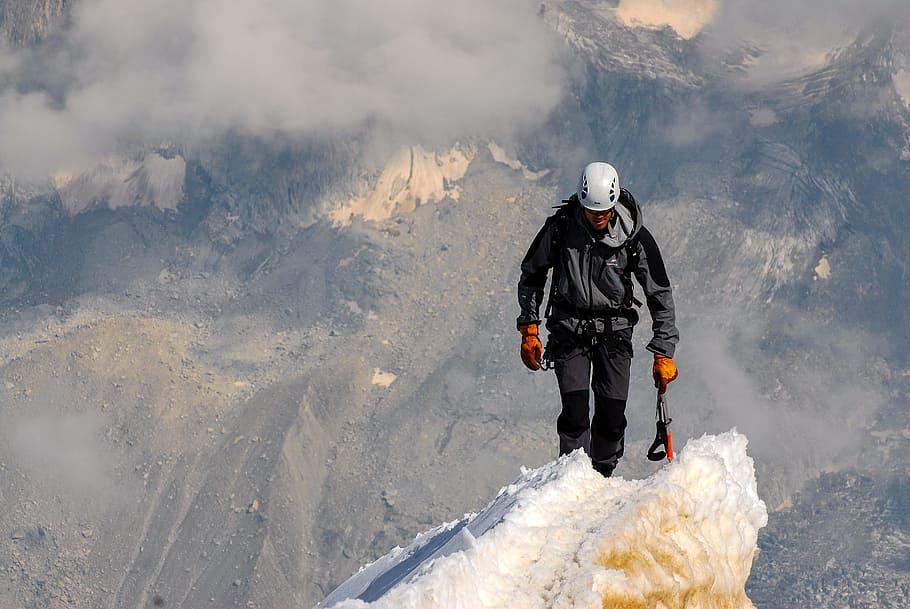 man wearing jacket walking on mountain covered in ice, summit