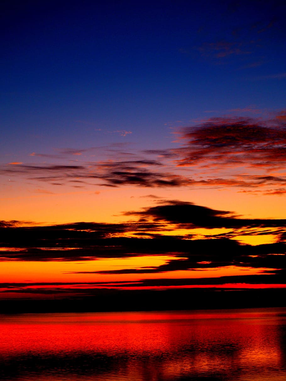 calm body of water under orange and black sky during golden hour HD wallpaper