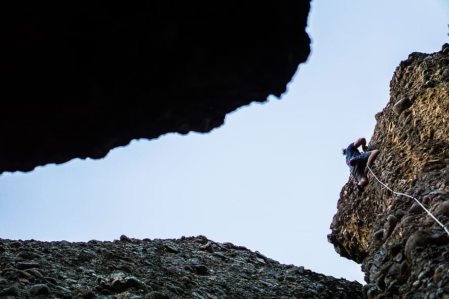 person on blue shirt and black shorts climbing cliff, person climbing on mountain HD wallpaper