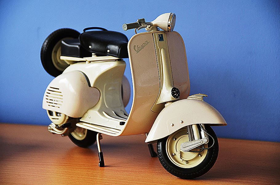 white and black motor scooter miniature on brown wooden surface
