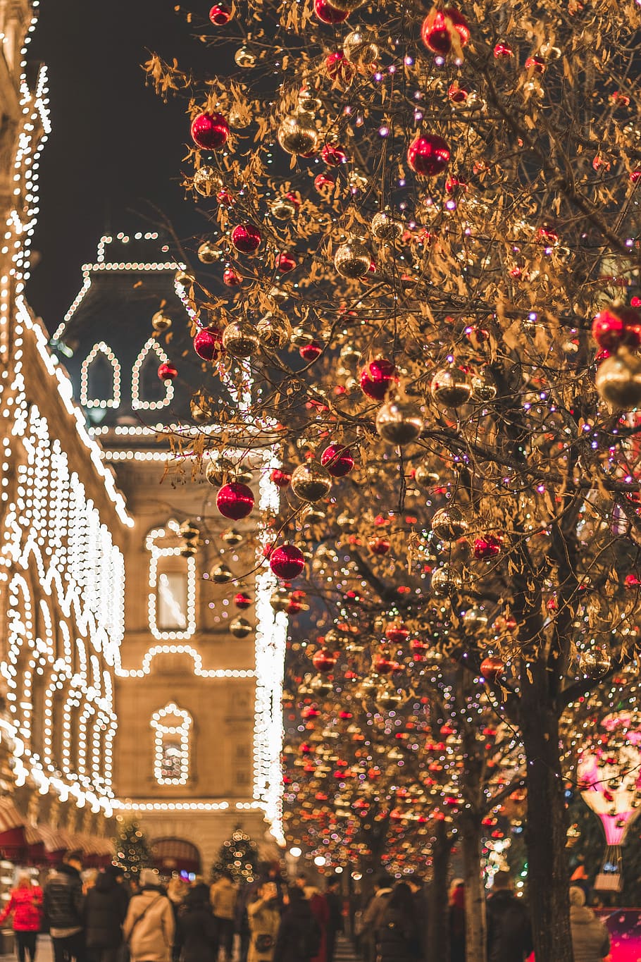 closeup photo of tree with baubles, people near building and trees during nighttime HD wallpaper