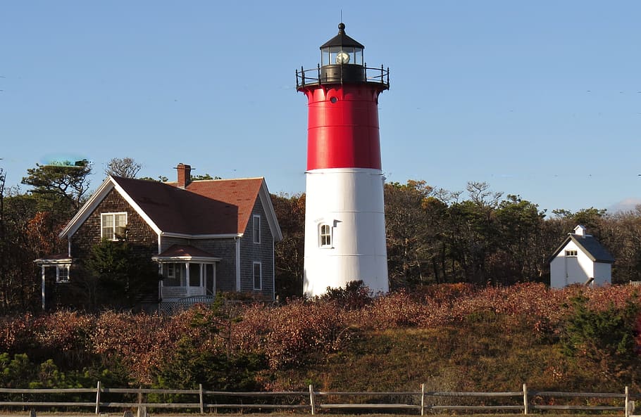 white and red lighthouse beside brown house under blue sky at daytime HD wallpaper