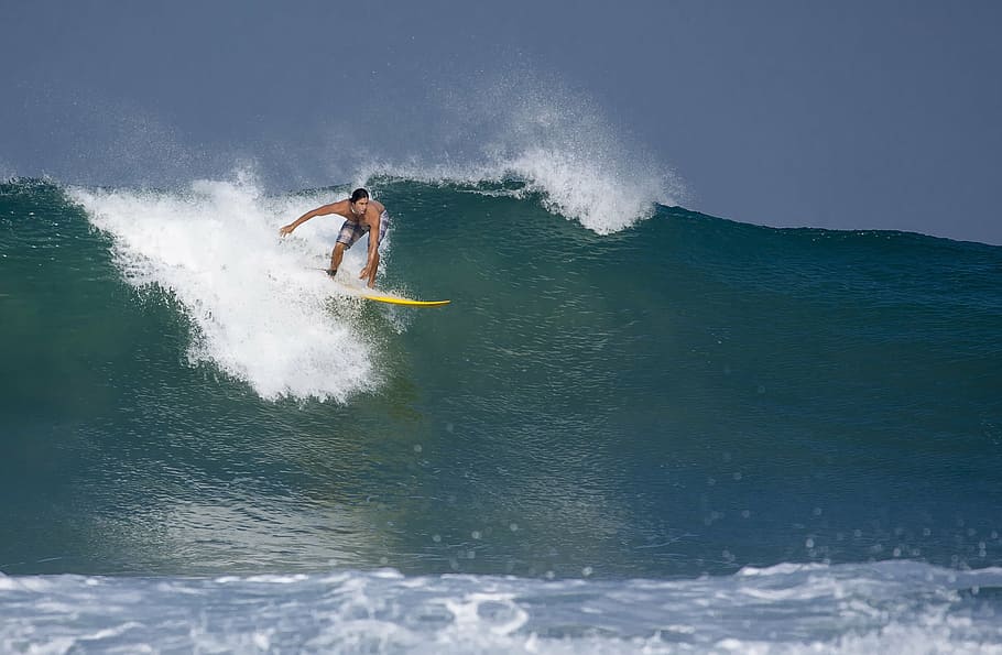 person surfing the wave with yellow surfboard under clear sky HD wallpaper