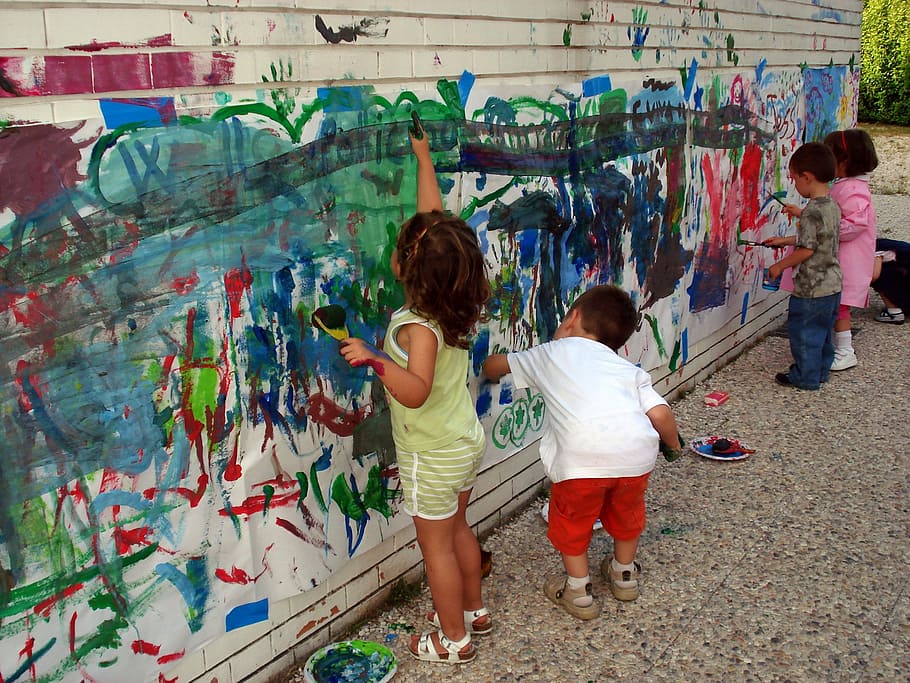 four children painting wall during daytime, hands, murals, colors
