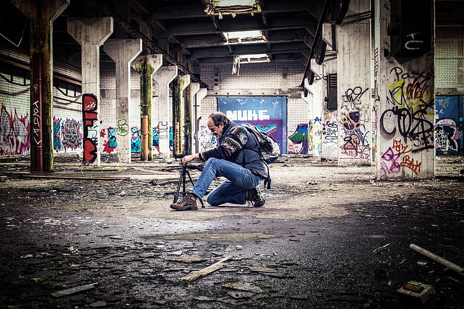 man wearing jacket and jeans holding camera stand inside the tunnel HD wallpaper