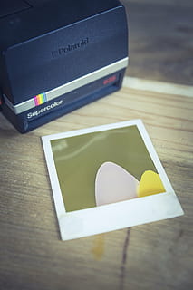 black Polaroid Supercolor instant camera on brown wooden surface HD wallpaper