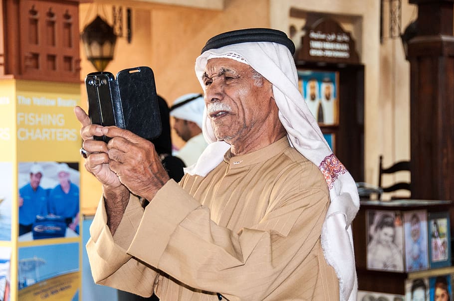 man holding smartphone near photo frame, dubai, arabs, human HD wallpaper