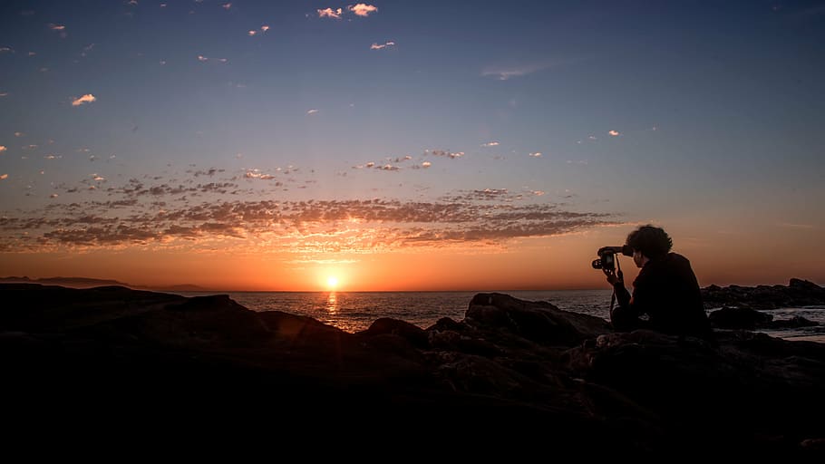 silhouette of person holding camera during golden hour, dawn HD wallpaper