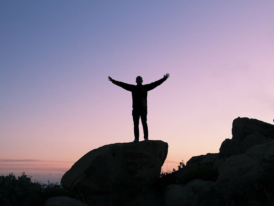 silhouette of person standing on rock, man, open, arms, sunset