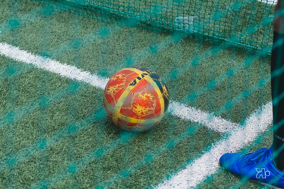 person standing in front of ball near net, red and yellow soccer ball HD wallpaper