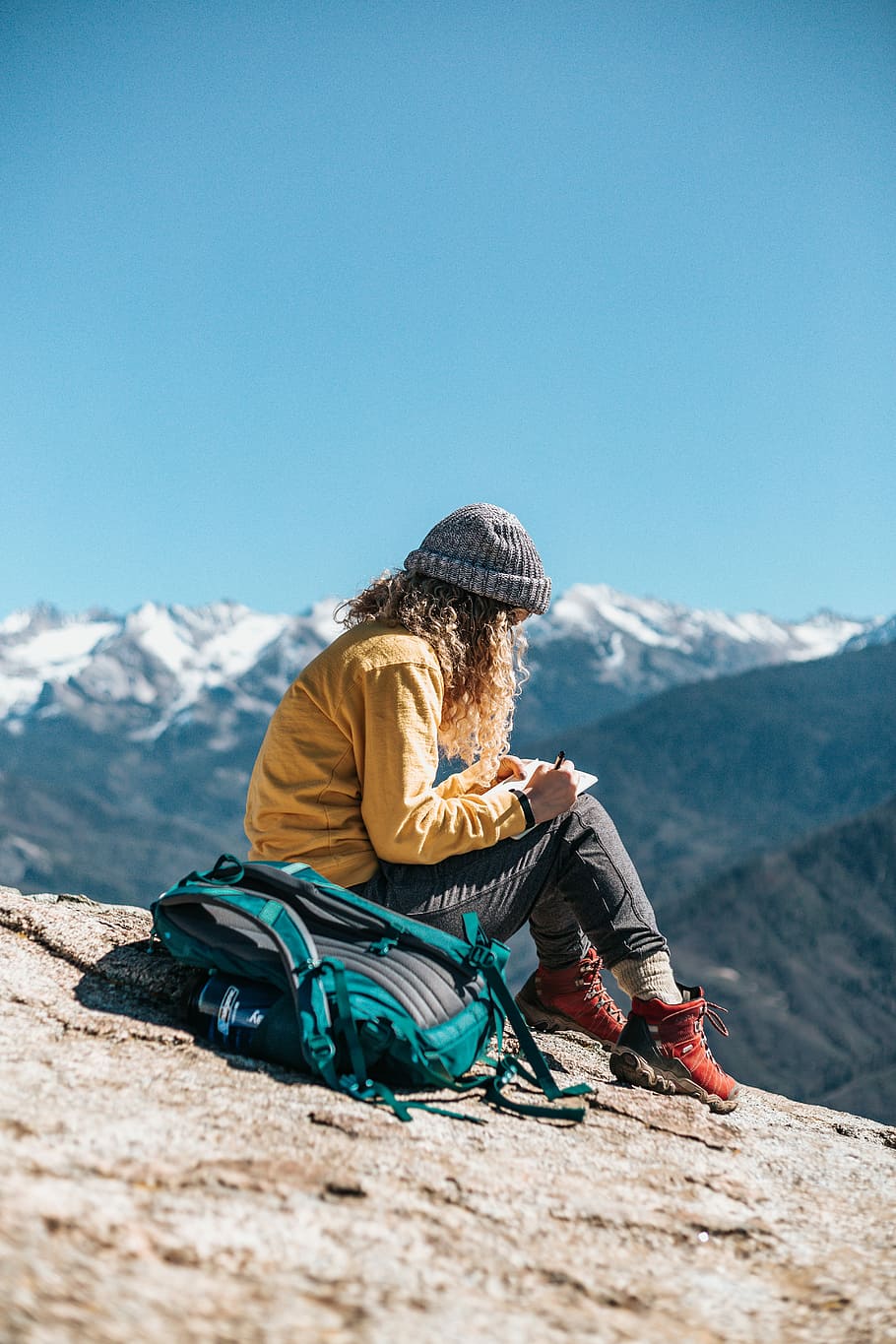 woman writing while sitting on hill near mountain, woman sketching mountains HD wallpaper