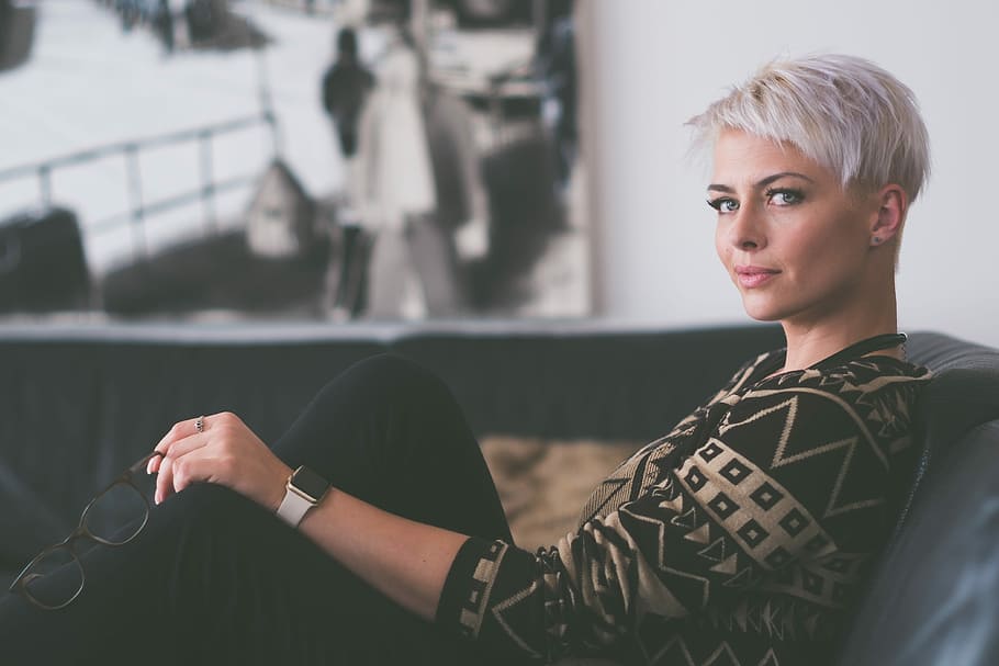 woman in black and white tribal print sweater sitting on black couch in tilt shift photography HD wallpaper