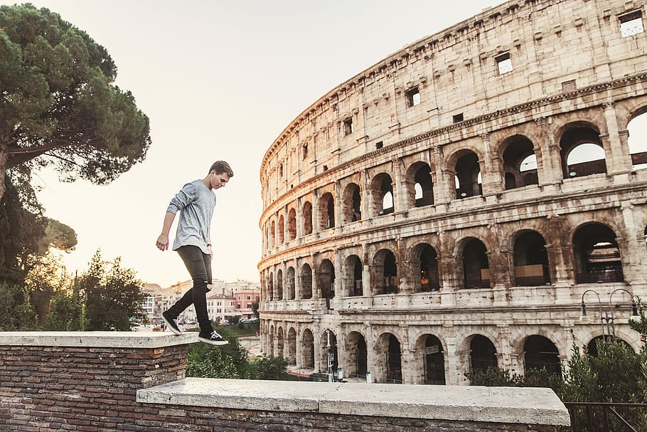 man jumping on edges, man walking above wall beside colosseum at daytime HD wallpaper