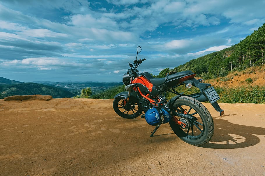 Photography of Orange and Black Sports Motorcycle Near a Cliff HD wallpaper