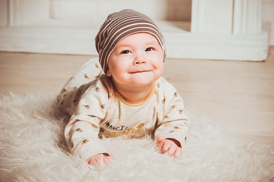 baby wearing brown sleep suit and gray knit cap in white fur floor rug, HD wallpaper