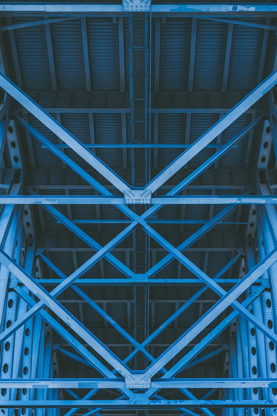 low-angle photography of grey metal beams and roof, blue metal ceiling structure
