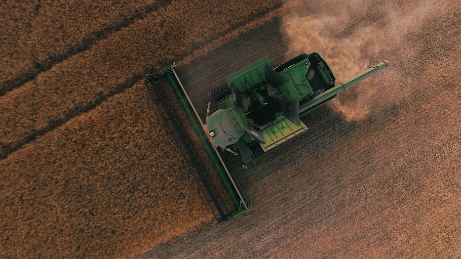 green farming equipment on brown field, aerial photography of green harvester