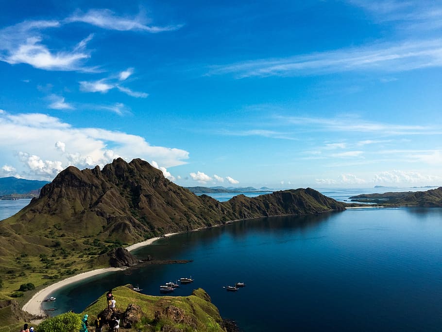 calm body of water next to green mountain under blue sky at daytime HD wallpaper