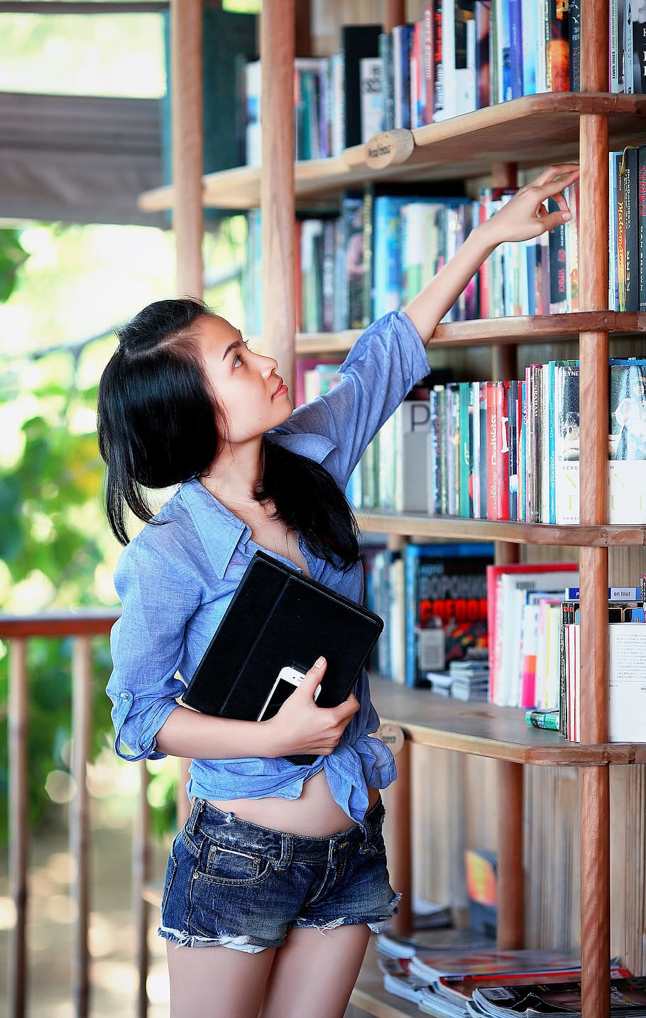 woman with blue sport shirt reaching of a book on a bookcase, HD wallpaper