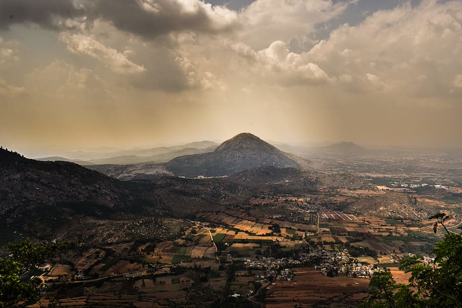 grass covered mountains near city during daytime, aerial photography of village and mountains under cloudy sky HD wallpaper