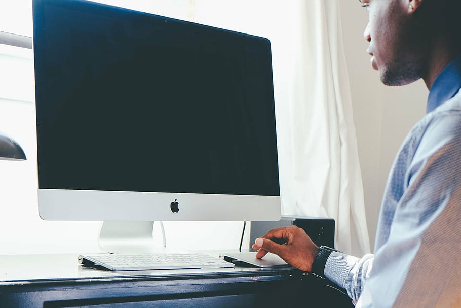 man's hand on silver Apple Track pad infront of silver iMac HD wallpaper